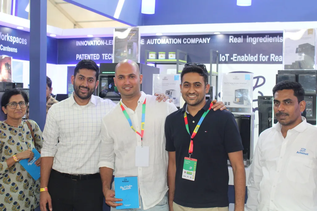 Automat team members and visitors in a group photograph at the booth