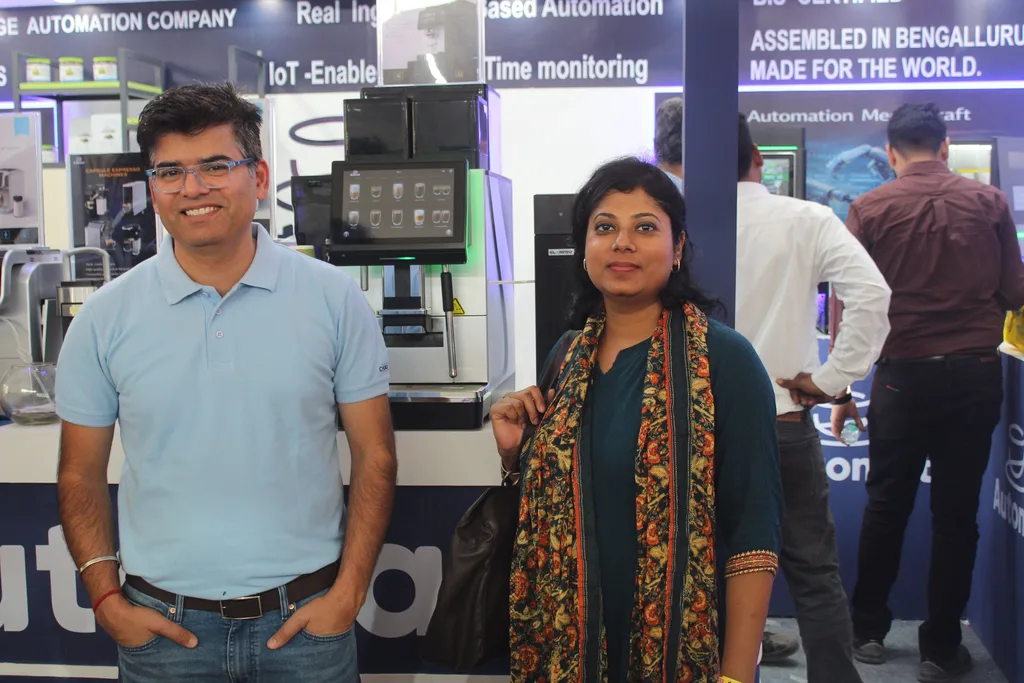 Two visitors at the Automat booth in front of coffee machines