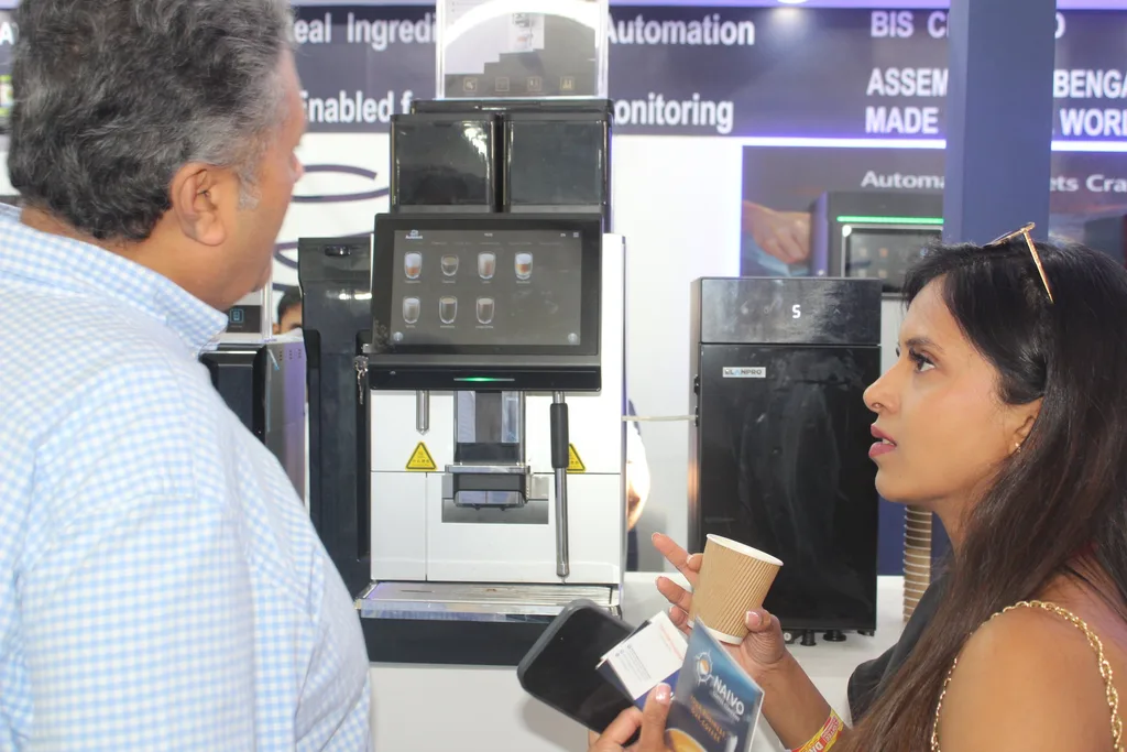Visitors with drinks beside an Automat coffee machine