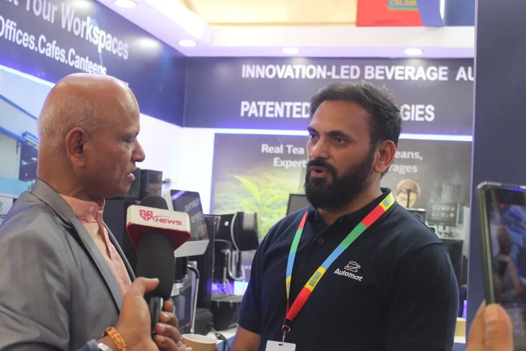 An Automat team member speaking to a media interviewer at the booth