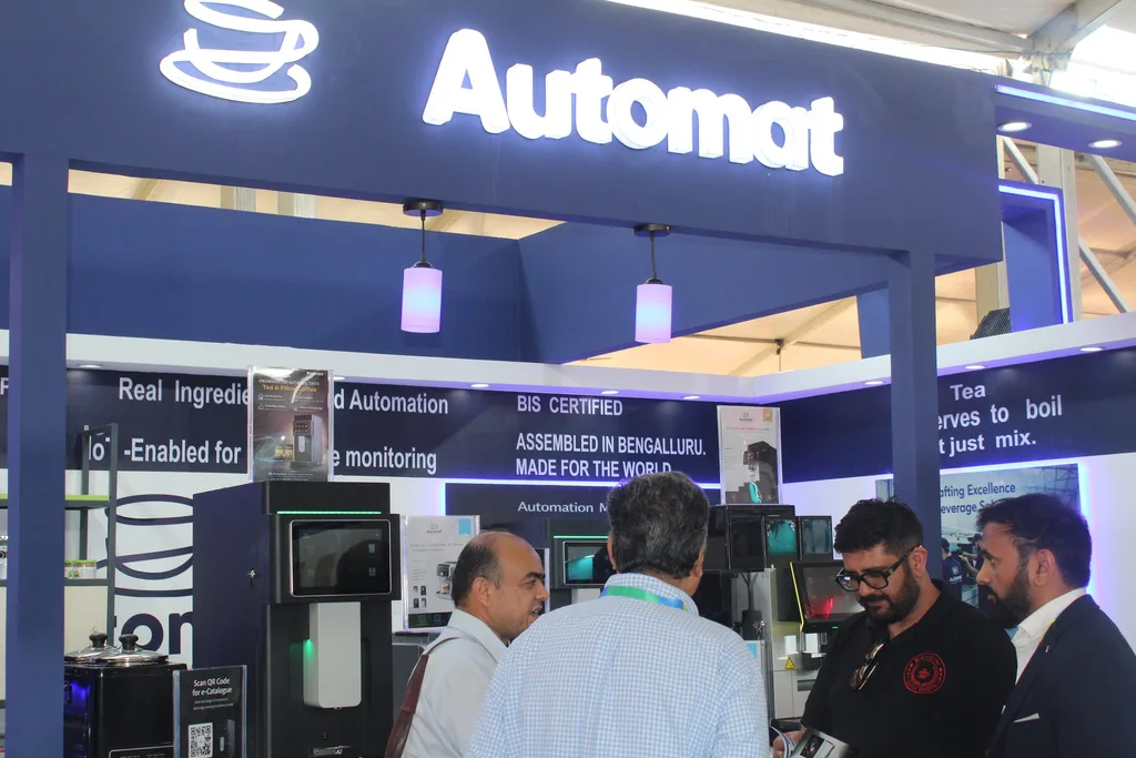 The Automat exhibition booth with tea and coffee machines on display and visitors