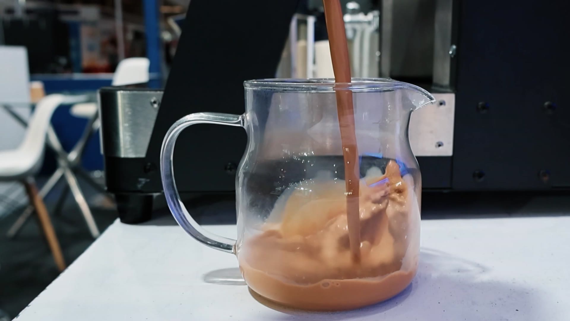 Fresh chai dispensing from BrewNex into a glass jug.