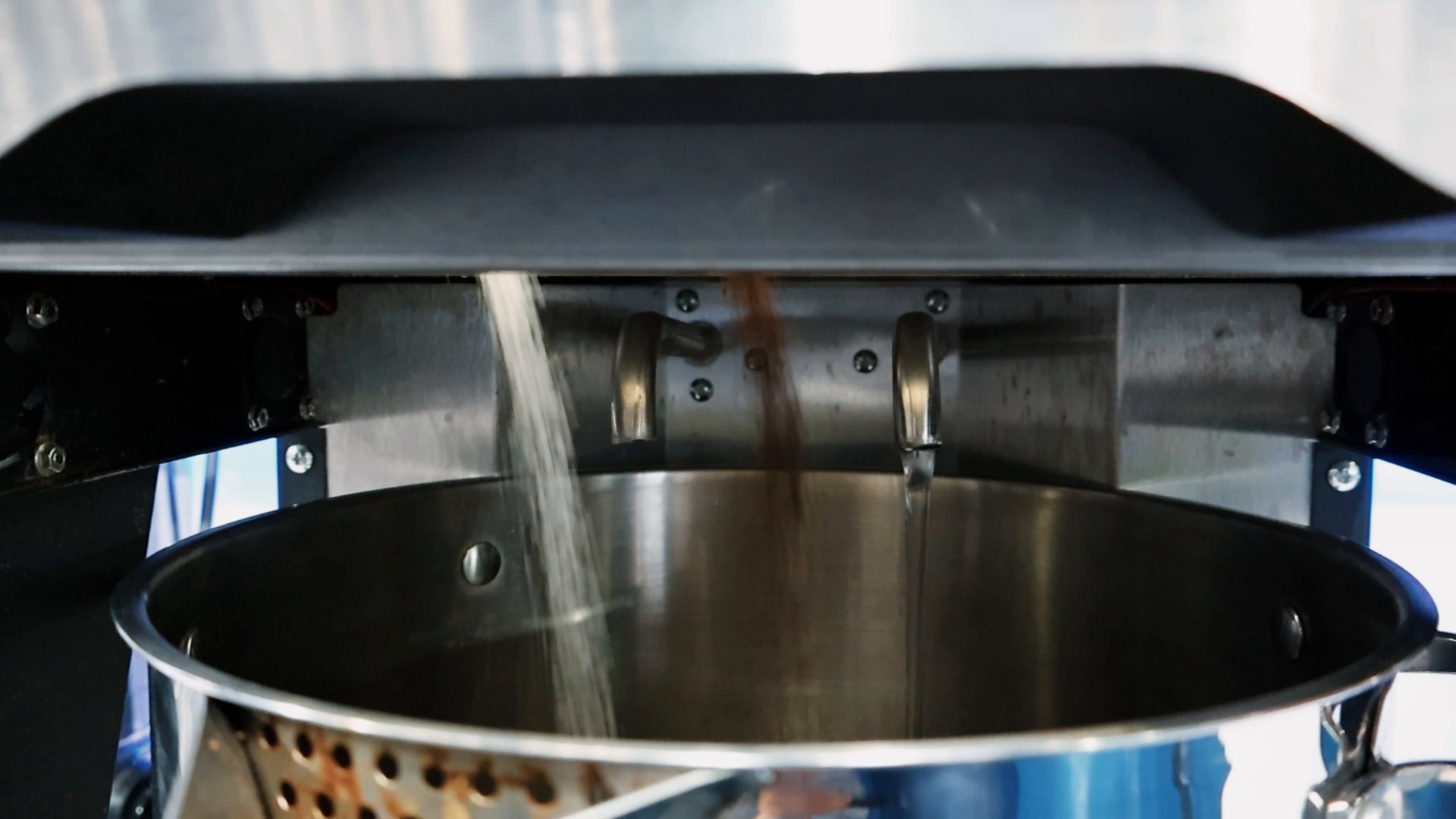 Dry ingredients falling from the BrewNex dispenser into the pot while liquid enters from a separate nozzle